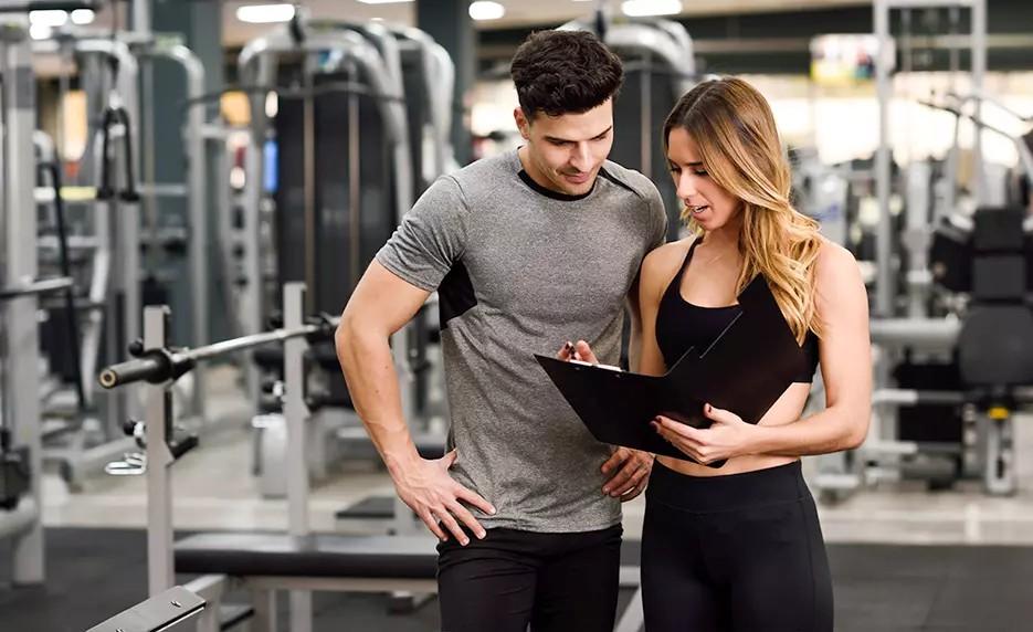 Personal trainer consulting with client in gym